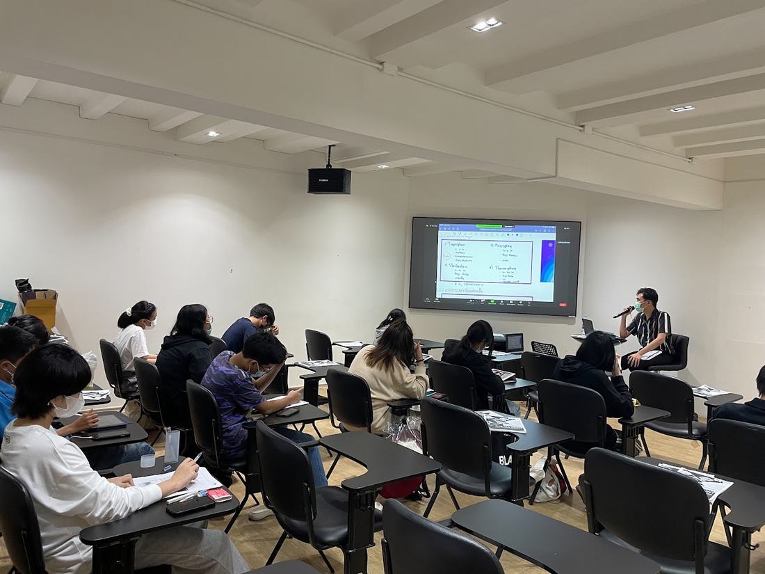 ห้องเรียนที่มีนักเรียนนั่งเรียนพร้อมกับการถ่ายทอดสดผ่าน Zoom